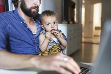 Porträt eines kleinen Jungen mit seinem Vater, der zu Hause einen Laptop benutzt - MASF04145