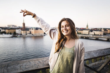 Optical illusion of happy female tourist holding building in city - MASF04147