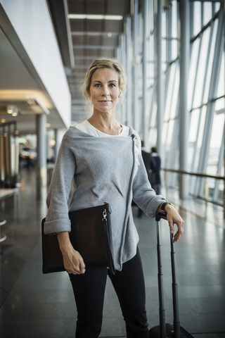 Porträt einer selbstbewussten Geschäftsfrau mit Gepäck auf einem Flughafen, lizenzfreies Stockfoto