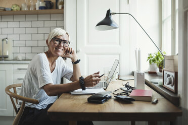 Portrait of happy designer sitting at table in home office - MASF04153