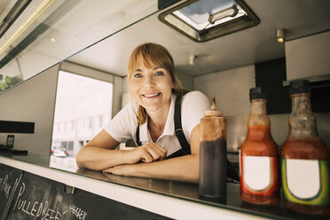 Porträt einer glücklichen Köchin, die sich an der Theke eines Food Trucks anlehnt - MASF04158