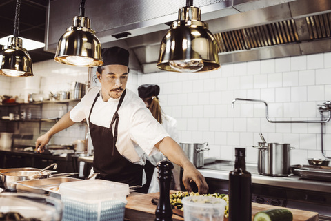 Manlig kock sträcker sig efter ingredienser i restaurangkök, lizenzfreies Stockfoto