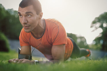 Man in plank position on grassy field at park - MASF04175