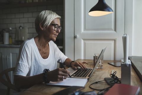 Reife Designerin arbeitet bis spät in die Nacht im Home Office, lizenzfreies Stockfoto