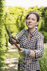 Ältere Frau schneidet Pflanzen mit einer Gartenschere - MASF04210