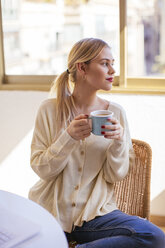 Blonde Frau mit Tasse Kaffee schaut aus dem Fenster - EBSF02391