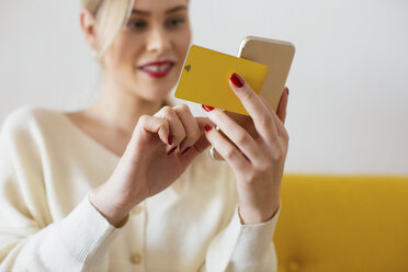 Frau nutzt Smartphone und verwendet Bankkarte zu Hause - EBSF02400