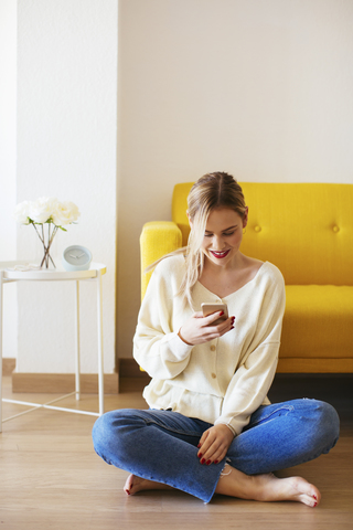 Blonde woman using smartphone at home stock photo