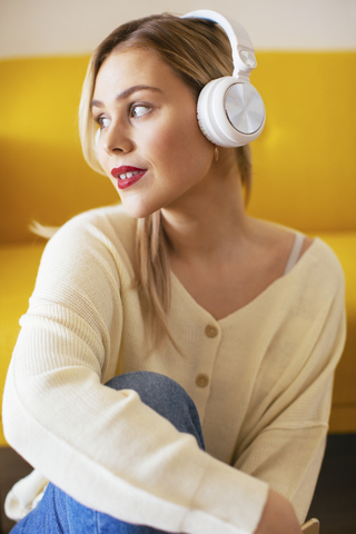 Blonde woman with headphones using smartphone at home stock photo