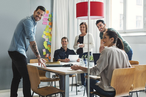 Happy team of business people discussing project at table in office stock photo