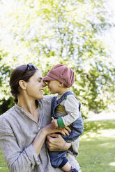 Happy mother and baby girl rubbing noses at park - MASF04262