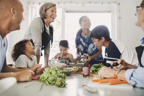 Happy multi-ethnic family preparing Asian food at kitchen stock photo