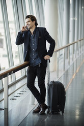 Happy businessman using smart phone at airport - MASF04270