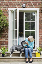 Glückliche ältere Frau mit Hund am Hauseingang - MASF04273