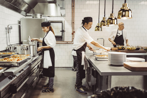 Kvinnlig och manlig kock arbetar i restaurangkök, lizenzfreies Stockfoto