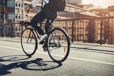 Tiefschnitt eines Geschäftsmannes, der auf einer Brücke in der Stadt Fahrrad fährt - MASF04286