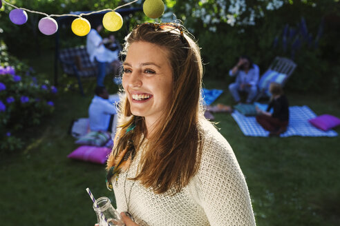 Happy young woman with friends in background at yard during summer party - MASF04316
