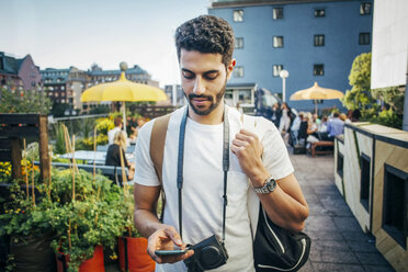 Männlicher Tourist benutzt ein Smartphone in der Stadt - MASF04324