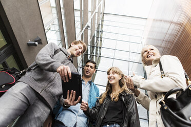 Low angle view of young friends using digital tablet in university - MASF04328