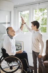 Behinderter Mann im Rollstuhl gibt seinem Sohn zu Hause ein High-Five - MASF04350