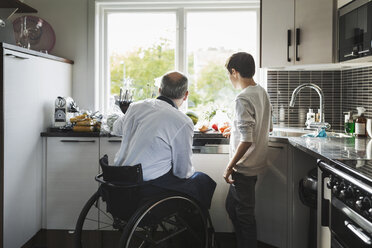 Behinderter Vater bereitet Essen zu Sohn in Küche - MASF04351