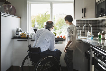 Disabled father preparing food son in kitchen - MASF04351