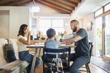 Family of three sitting at dining table in house - MASF04359