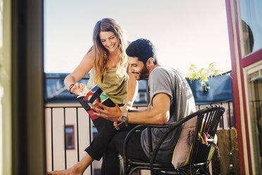 Couple reading guidebook together on balcony - MASF04381