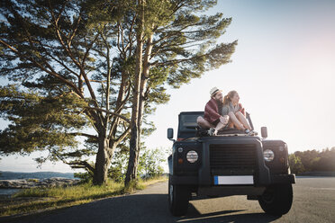 Couple sitting on jeep at countryside - MASF04382