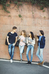 Full length of teenagers talking while leaning on wall - MASF04405