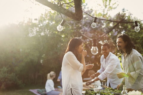 Freunde bereiten während eines Sommerfestes im Hinterhof gemeinsam Essen zu, lizenzfreies Stockfoto