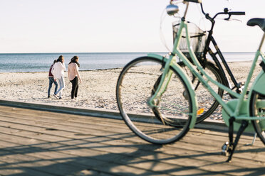 Strandspaziergang von Freunden in voller Länge mit Fahrrädern im Vordergrund - MASF04415