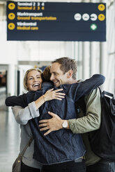 Happy business colleagues embracing at airport - MASF04427