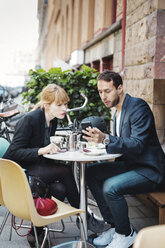 Geschäftspendler benutzen ihr Smartphone in einem Straßencafé - MASF04439