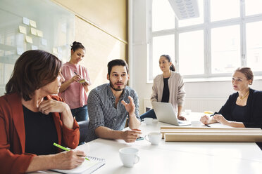 Businessman explaining new project to female colleagues at conference table - MASF04461