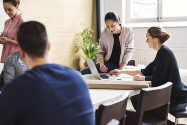 Businesswomen using laptop at table in meeting room - MASF04462