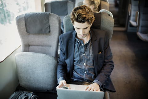 Geschäftsmann mit Laptop im Zug, lizenzfreies Stockfoto