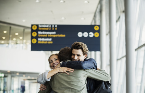 Affectionate business colleagues embracing at airport stock photo