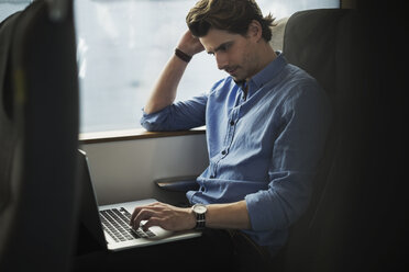 Businessman using laptop while traveling in train - MASF04480