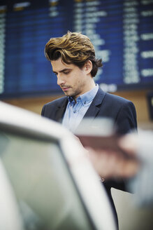 Geschäftsmann steht am Flughafen Check-in-Schalter - MASF04481