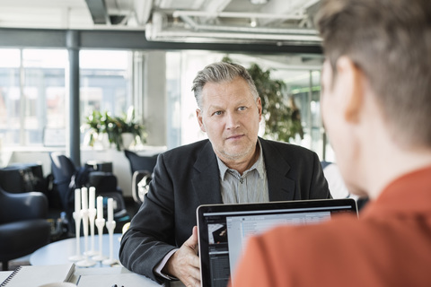 Geschäftsmann, der einen Kollegen während einer Besprechung ansieht, lizenzfreies Stockfoto