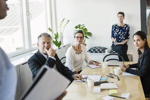 Geschäftsleute, die einen männlichen Kollegen während einer Besprechung im Büro ansehen - MASF04489