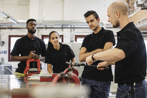 Automechaniker-Lehrer erklärt den Schülern die Ausrüstung im Unterricht, lizenzfreies Stockfoto