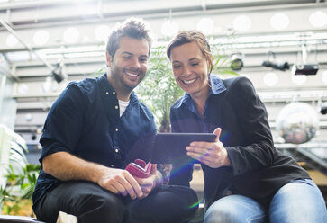 Lächelnde Geschäftsleute teilen sich ein digitales Tablet im Café - MASF04509