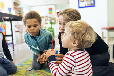 Erzieherin und Kinder spielen mit Seifenblasen im Kindergarten - MASF04532