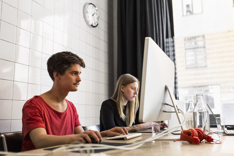 Junger Geschäftsmann und Geschäftsfrau nutzen Technologien im neuen Büro, lizenzfreies Stockfoto