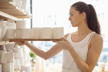 Young female worker arranging craft products in crockery workshop - MASF04572