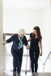 Young woman helping grandmother to climb steps - MASF04586