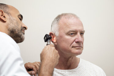 Doctor using otoscope while examining patient's ear in hospital - CAVF38468