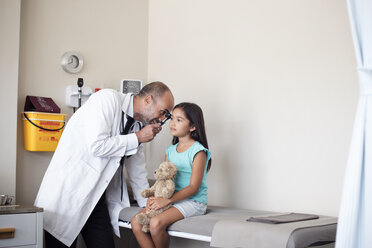 Doctor using otoscope for checking girl's ear in medical examination room - CAVF38489